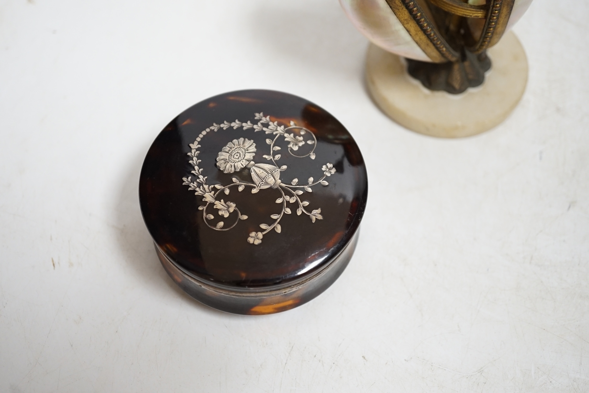A Victorian tortoiseshell and silver piqué inlaid circular lidded snuff box and a Palais Royale mother-of-pearl and ormolu needlework case, largest 13cm high. Condition - fair, case does not snap shut
